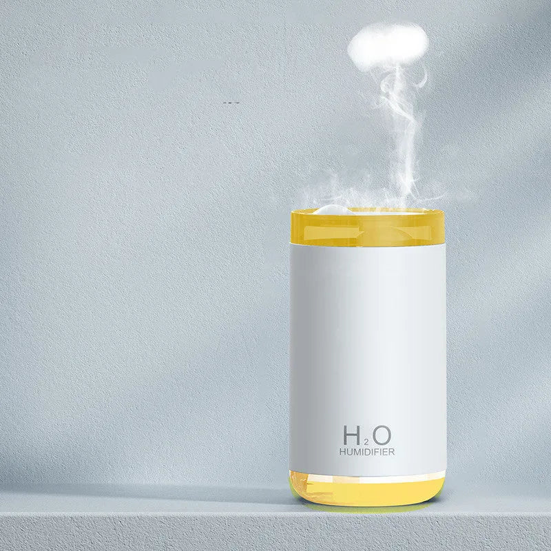 White USB humidifier with jellyfish spray mist effect and warm night light on a table.