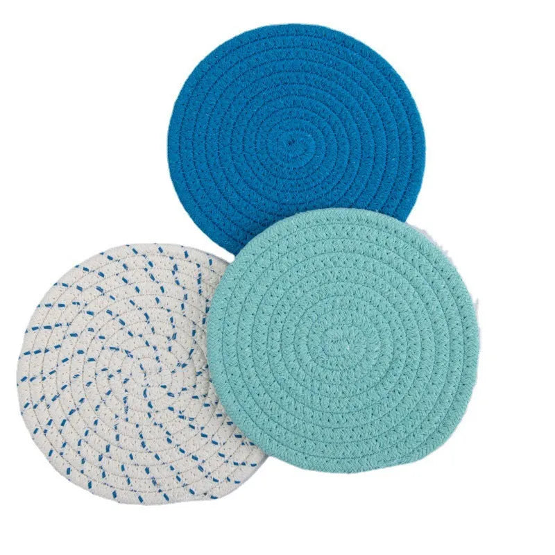 Three round grey cotton cord coasters on a wooden table