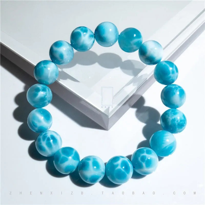 Blue handmade bodhi bracelet with natural crystal sea-pattern beads and pearl accents on a white background.