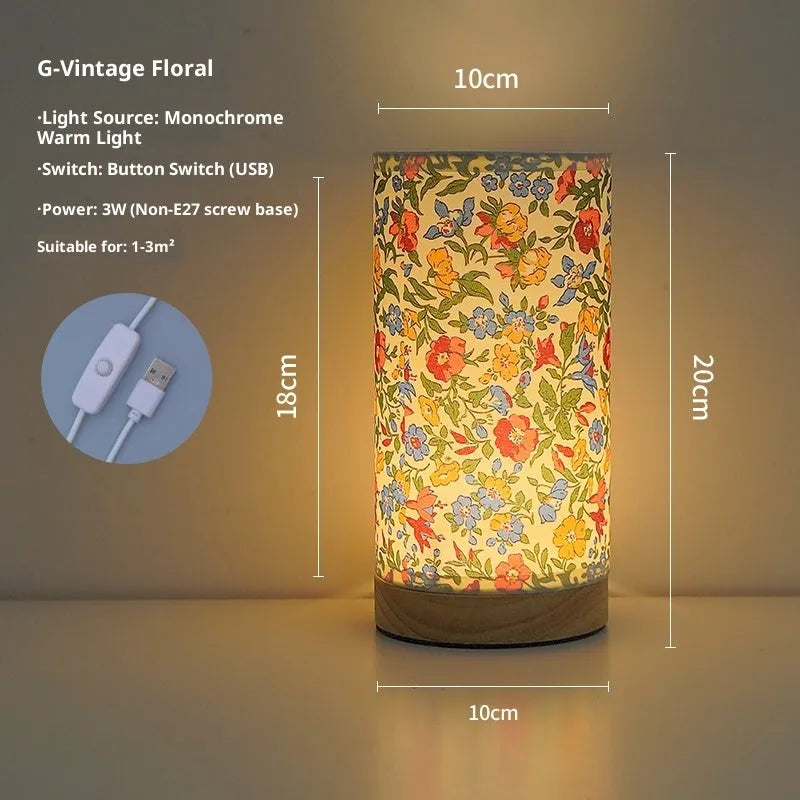 Creative floral fabric table lamp with remote control, warm LED light, black oil painting pattern on a bedside table