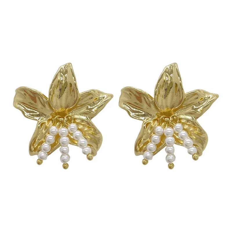 A pair of exaggerated gold metal flower earrings with pearl details, showing a niche jewellery style.