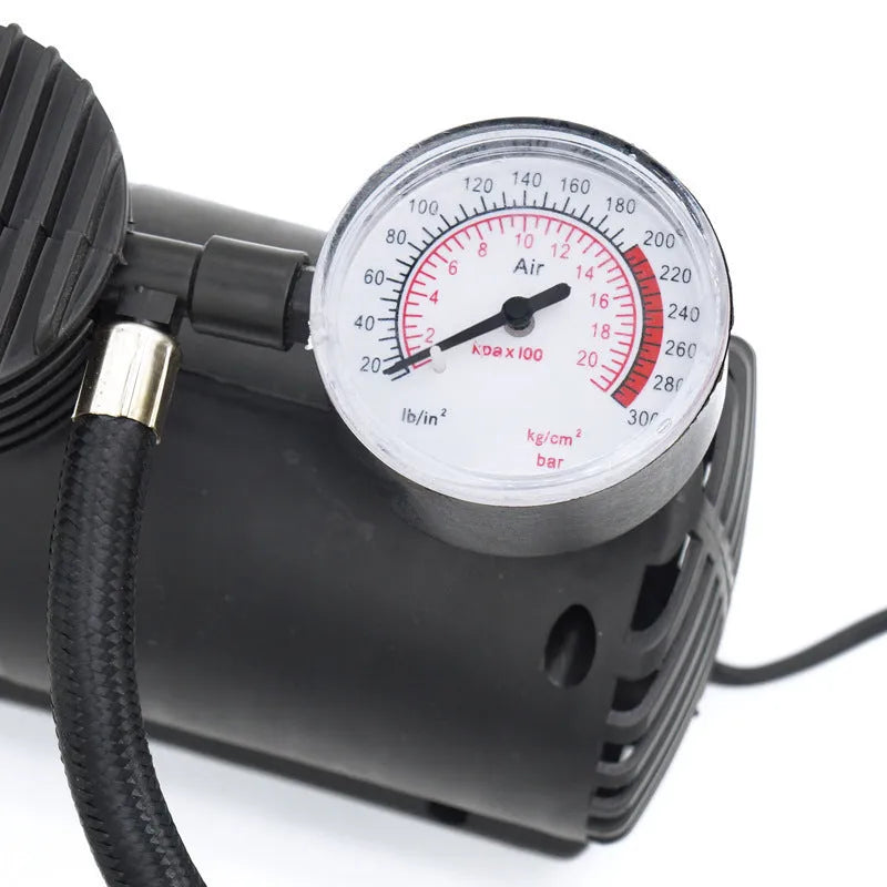Black 12V portable mini air compressor with 300 psi gauge, 9-foot cord, and two adapter nozzles on a neutral background