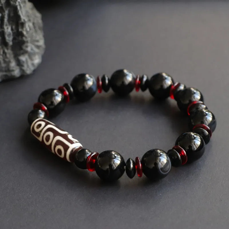 Hand-woven black agate dzi bead bracelet with geometric design measuring 11mm diameter