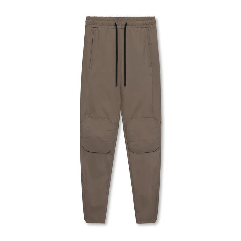 Man wearing dark grey loose-fit ankle-tied polyester running trousers for fitness.