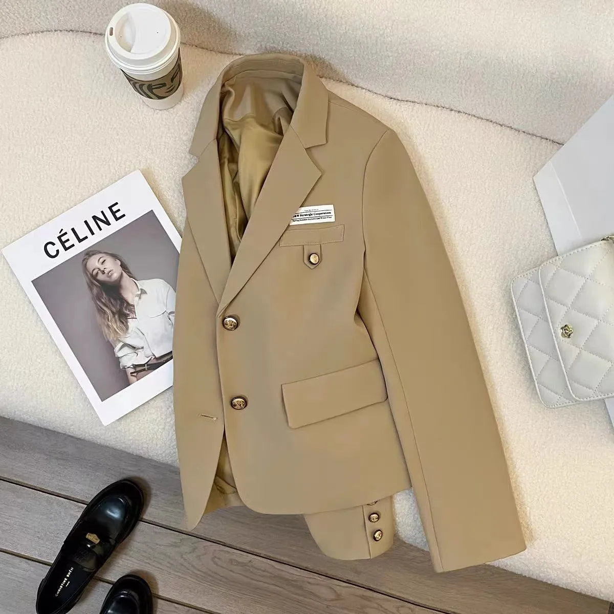 Women's black loose-fit short suit coat with regular sleeves and pockets on a hanger.