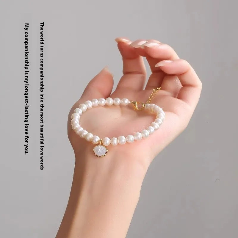 Close-up of a women's freshwater pearl fan bracelet on a wrist, showing elastic string and chain fastening options.