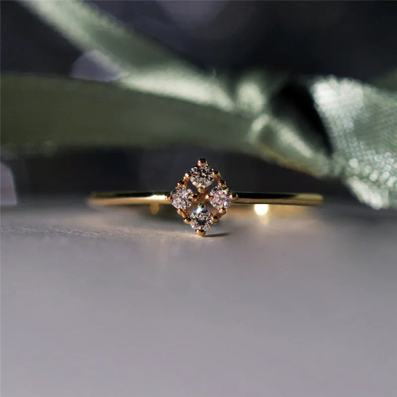 Four heart-shaped motif gold rings with zircon stones set on a dark surface
