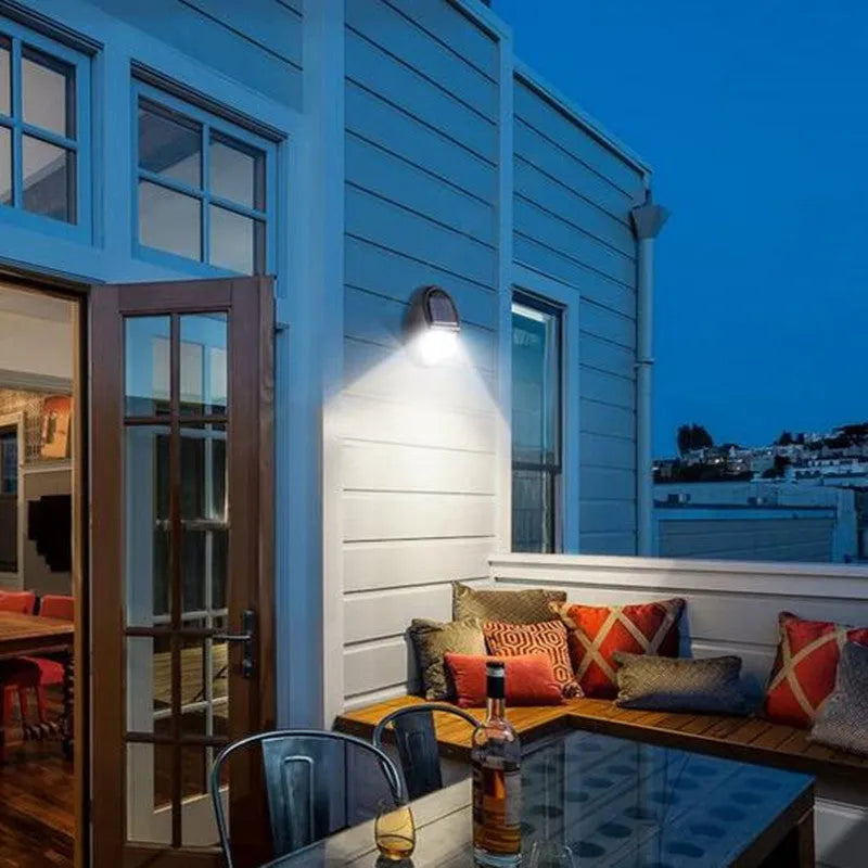 Black rectangular LED solar wall light mounted on an exterior wall for automatic night-time illumination.