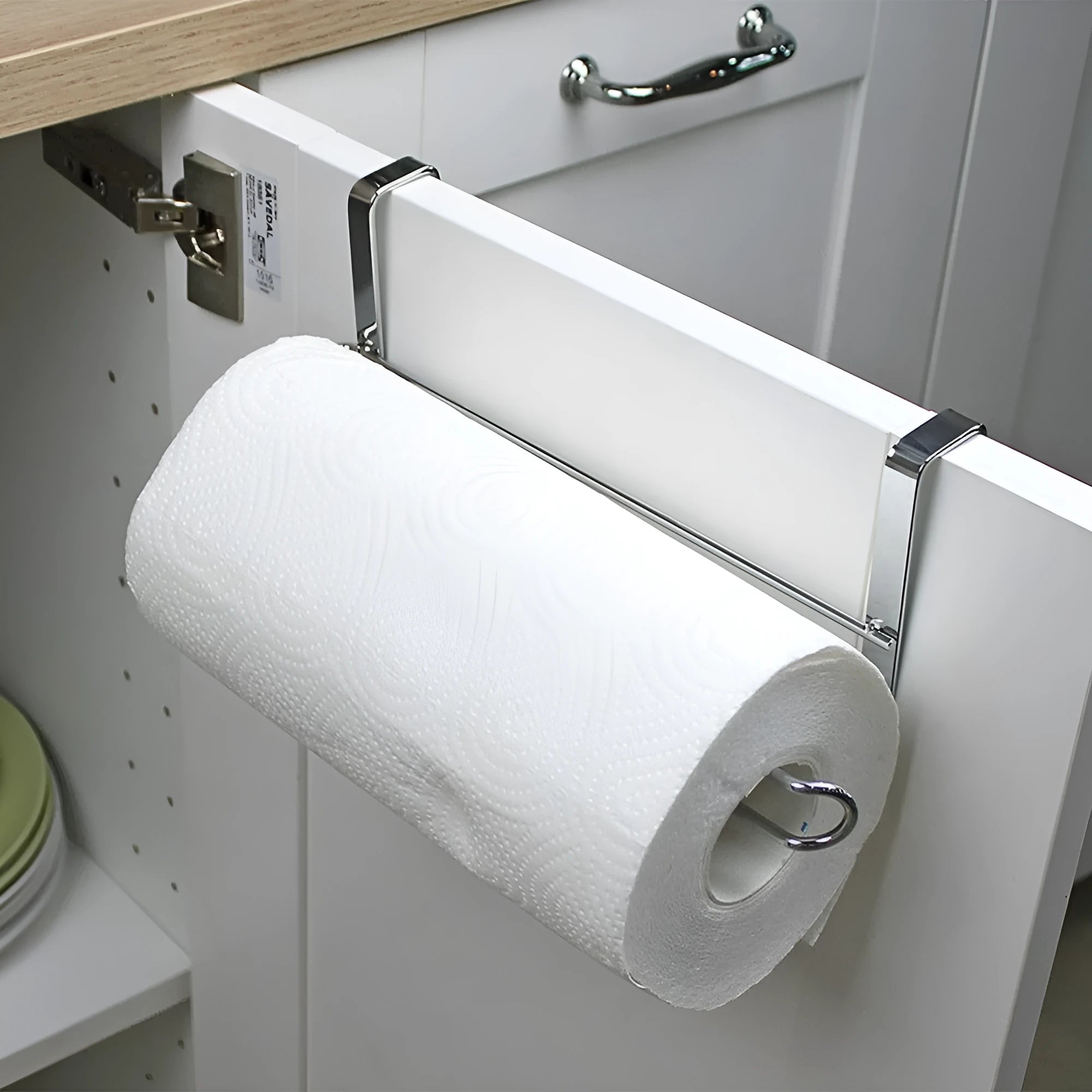 Silver stainless steel paper towel rack hanging on a cabinet door.