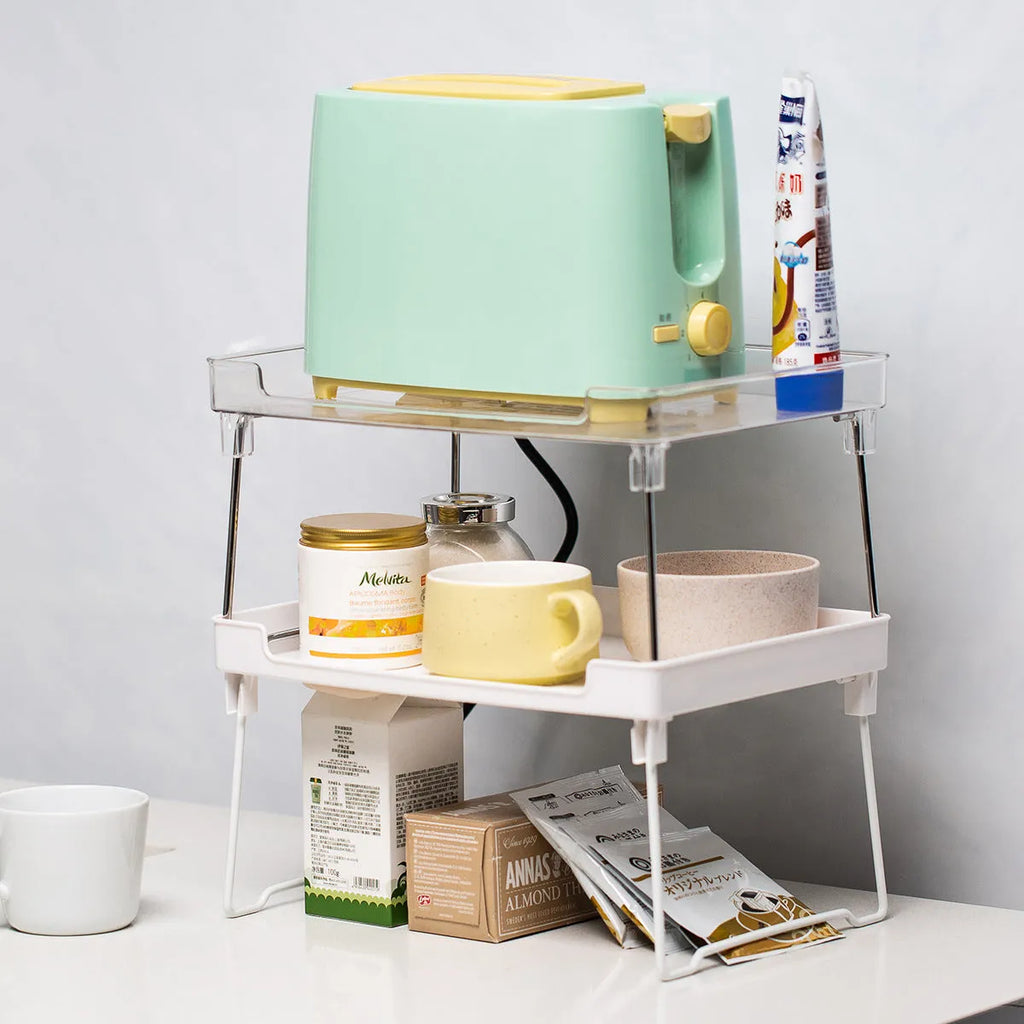 A transparent plastic kitchen storage rack holding utensils and spice jars on a countertop.
