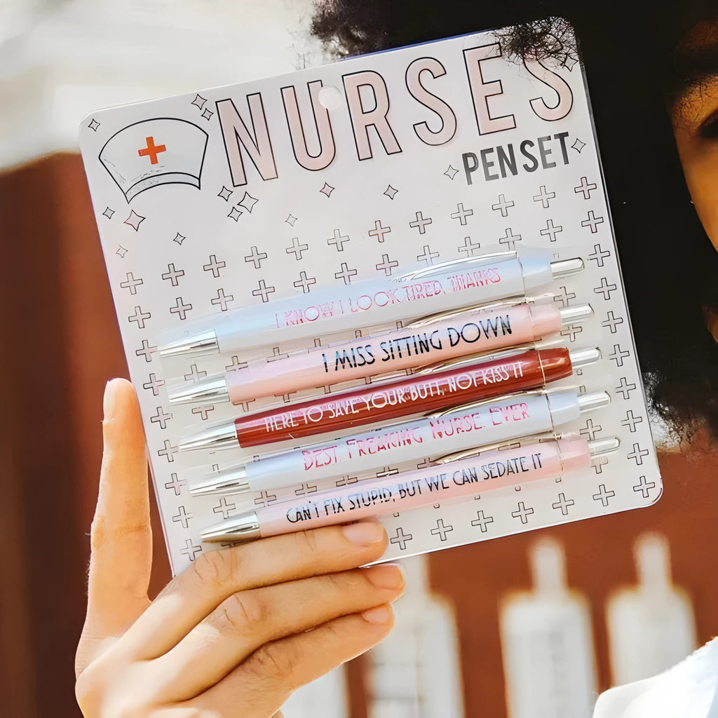 Set of five white plastic retractable ballpoint pens with blue and red nurse-themed humorous text printed on the barrels.