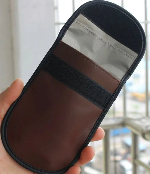 Black microfibre Faraday pouch for blocking car key, phone, and bank card signals, shown with a key fob inside.