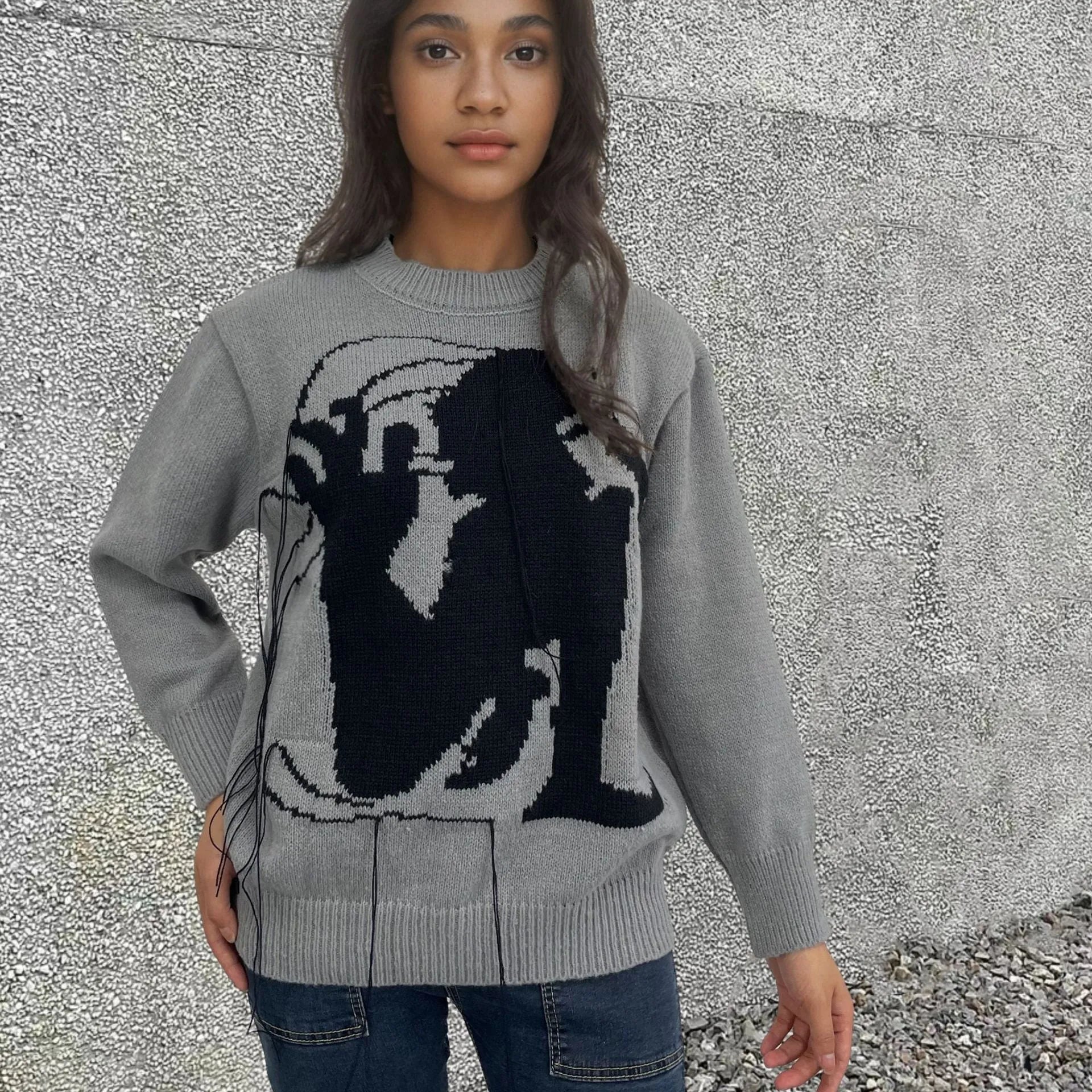 Grey women's loose alpaca wool sweater with abstract pattern and tassel design details on sleeve.