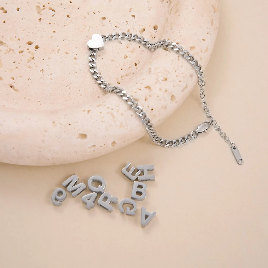 Gold and silver titanium steel necklaces showing letter A, number 7, and love heart charms on a 40.5cm chain.