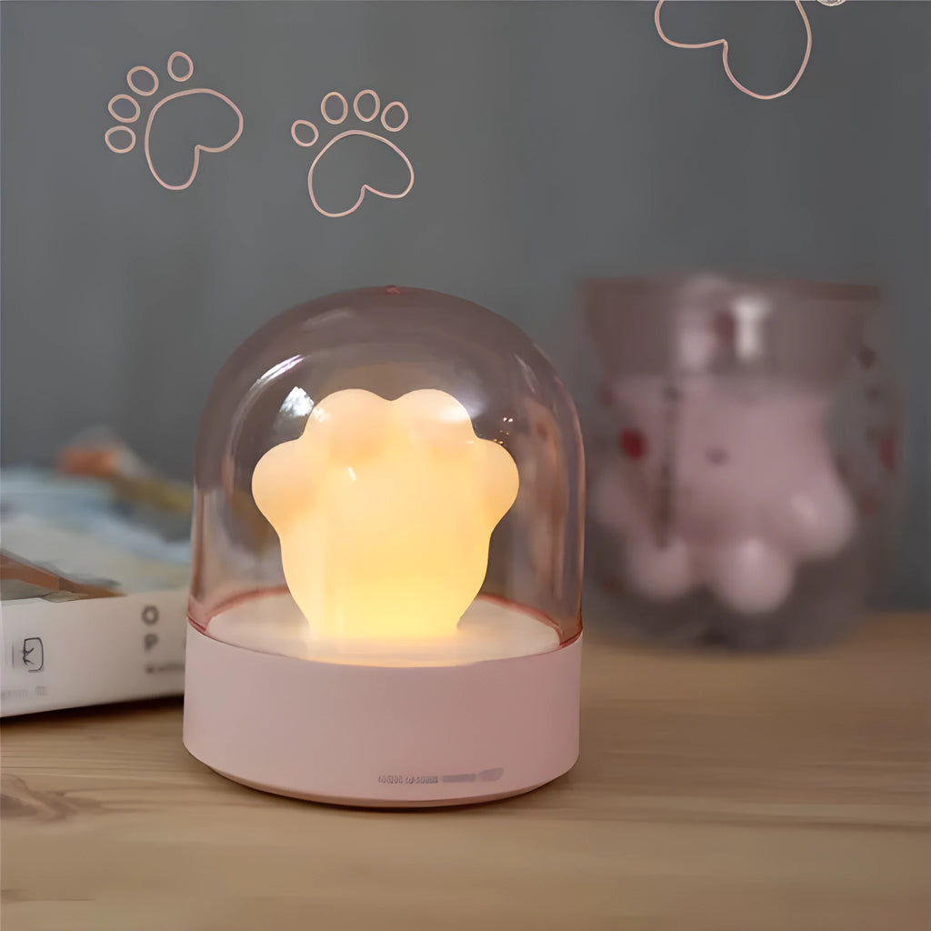 Grey and pink cat paw shaped USB night light with rotating lighting and music box features on desktop