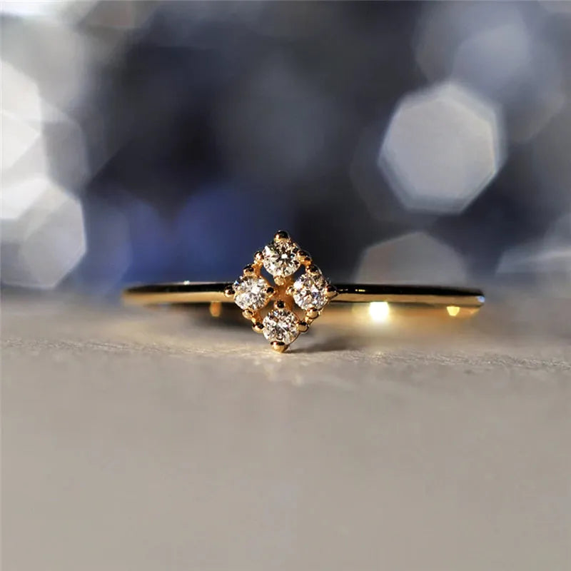 Four heart-shaped motif gold rings with zircon stones set on a dark surface