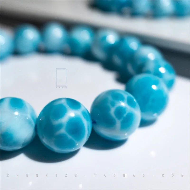 Blue handmade bodhi bracelet with natural crystal sea-pattern beads and pearl accents on a white background.
