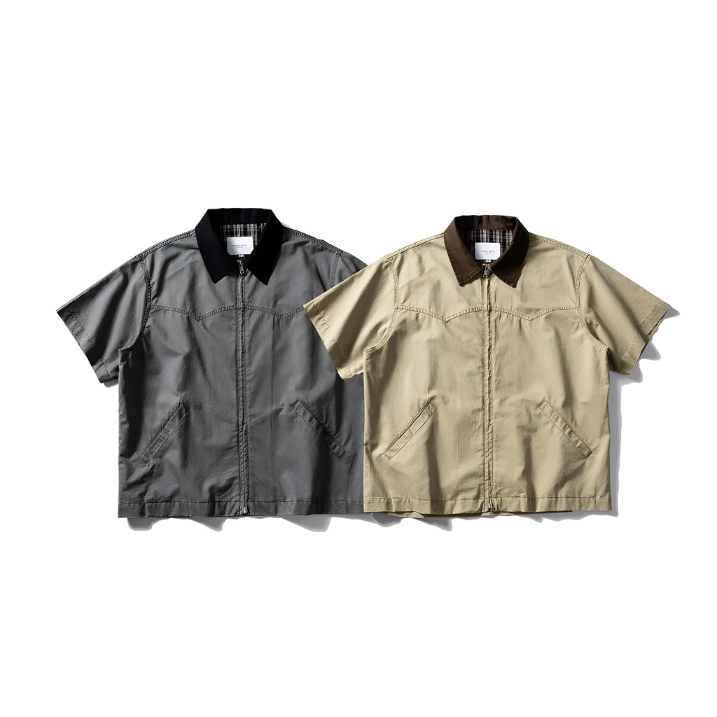 A man's khaki loose-fit short-sleeve cotton overalls shirt with button front and patch pockets.