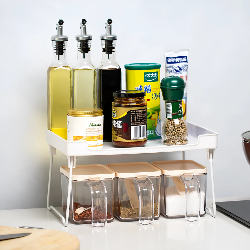 A transparent plastic kitchen storage rack holding utensils and spice jars on a countertop.