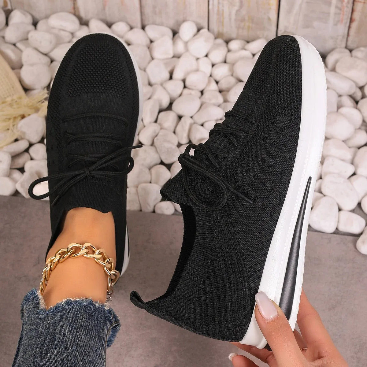 Women's black fly-knit style casual sneakers with lace-up front and low-top design.