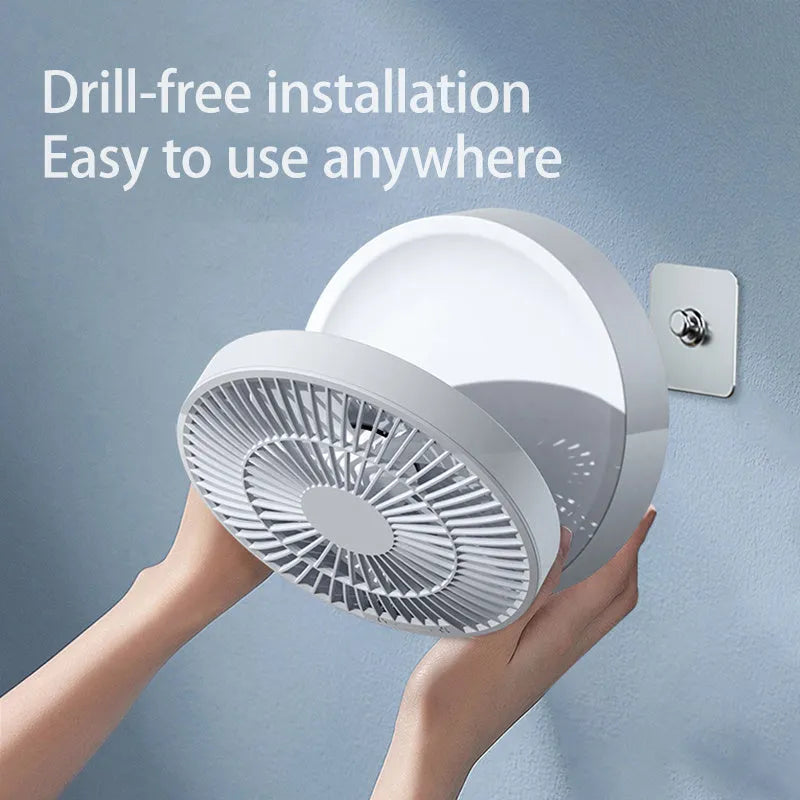 White portable folding fan with remote control on wooden desktop next to USB charging cable