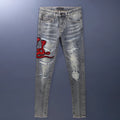 Slim fit light blue jeans with distressed knee patches, embroidery detail, and a faded wash.