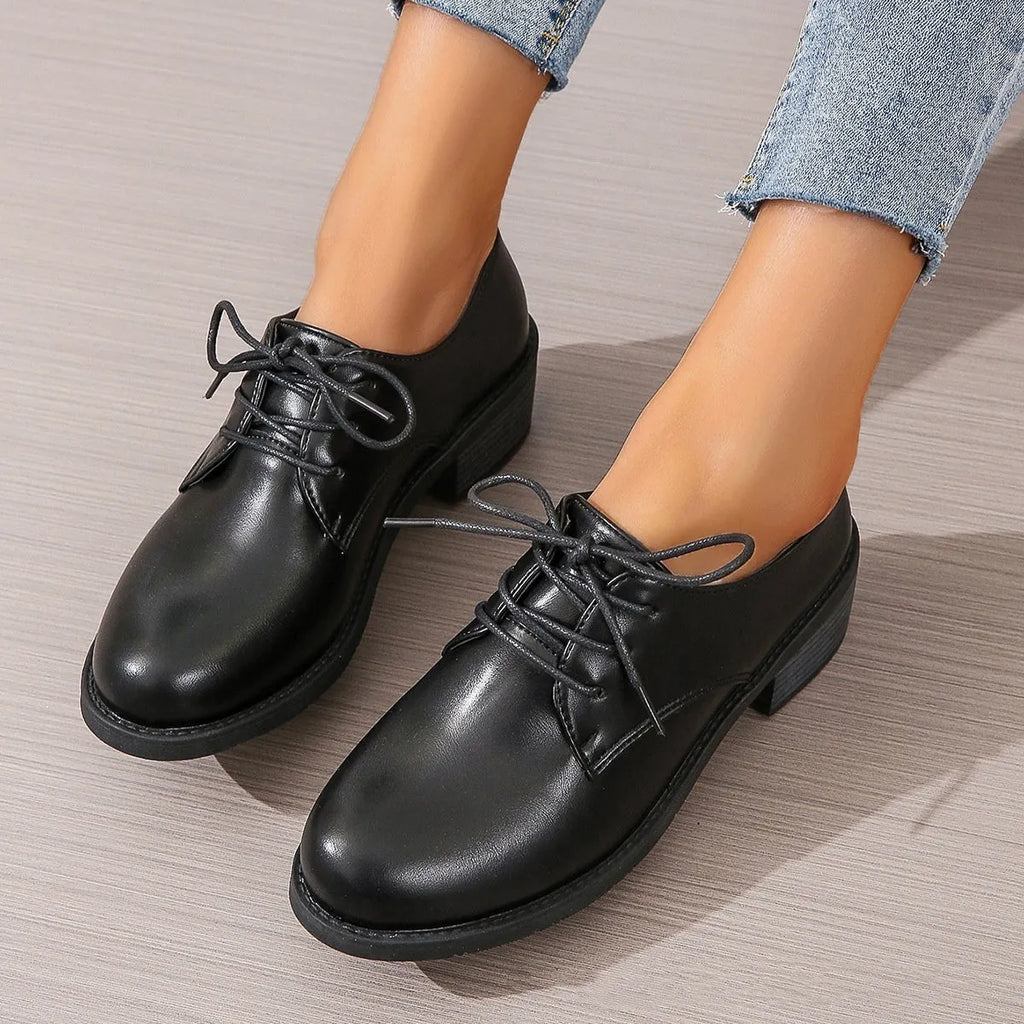 Black women's low-top work shoes with a chunky mid heel and soft rubber sole.