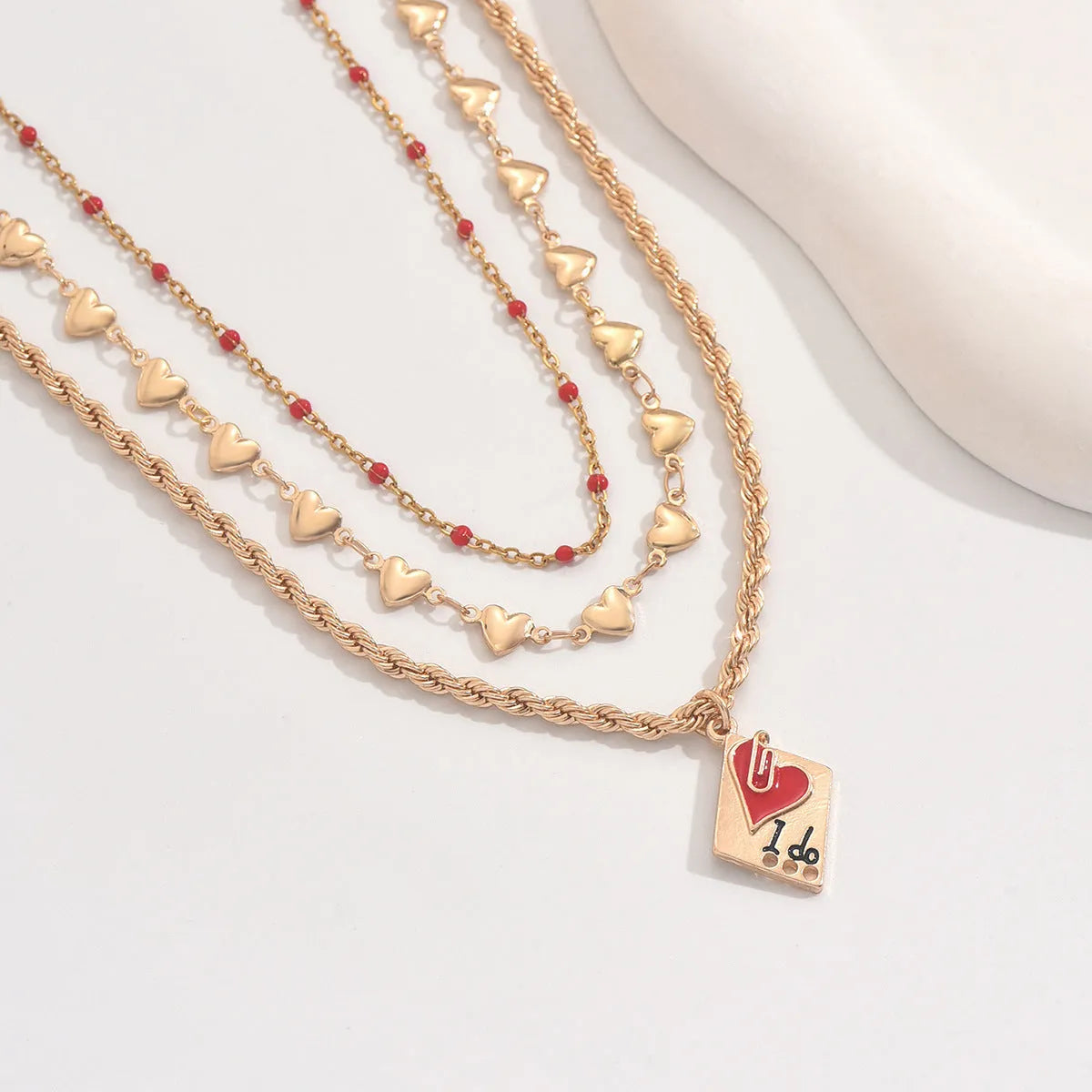 Silver-tone adjustable clavicle chain necklace with a geometric heart pendant on a three-layer chain.