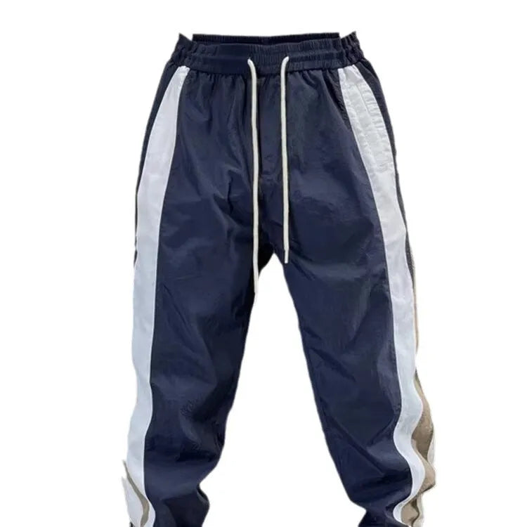 Men's loose fit contrast stripe jogger sports pants in black, showing drawstring waist and tapered leg