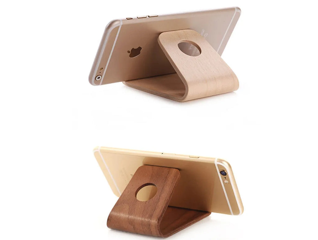 Wooden iPhone stand in walnut finish on a desk holding a mobile phone.