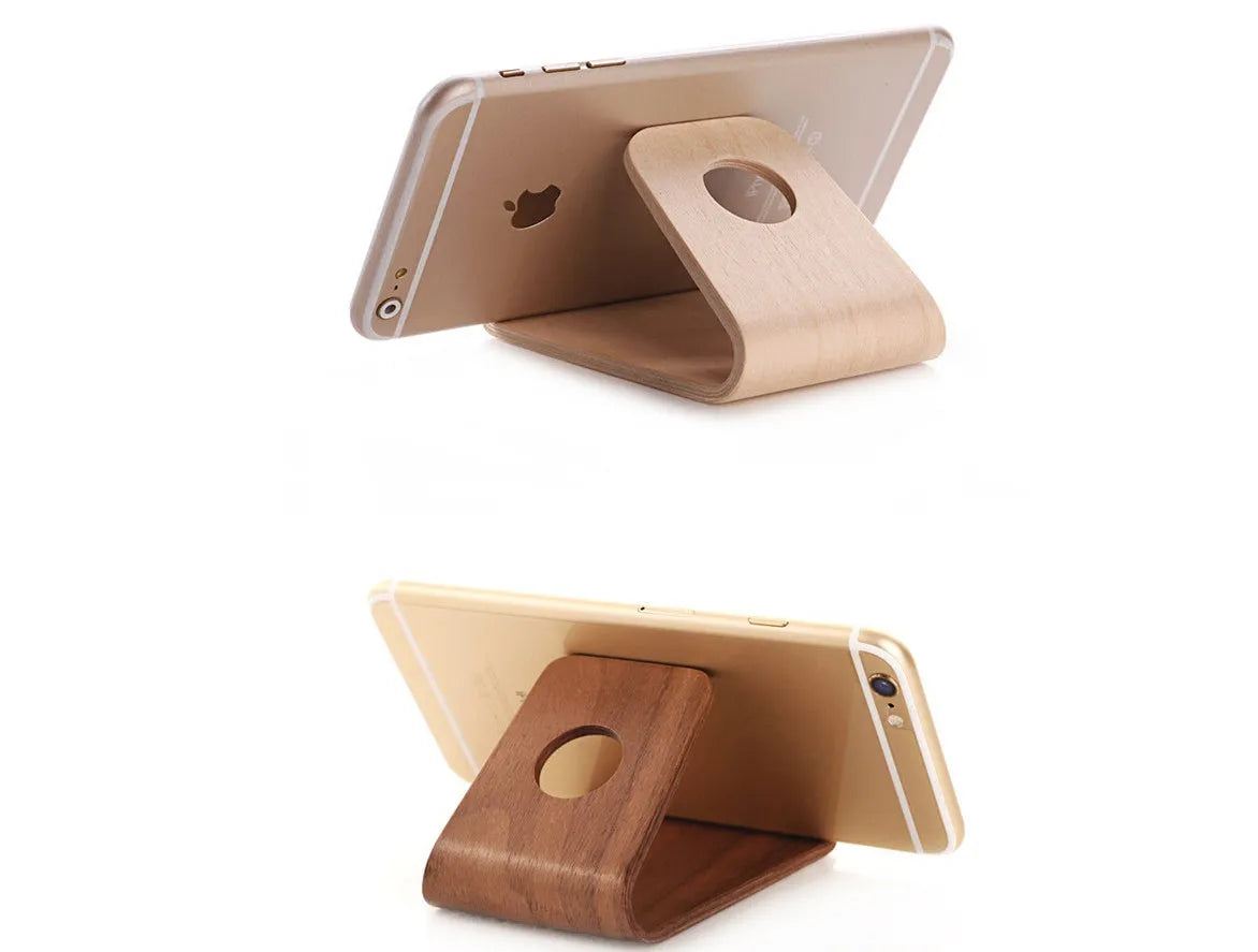 Wooden iPhone stand in walnut finish on a desk holding a mobile phone.
