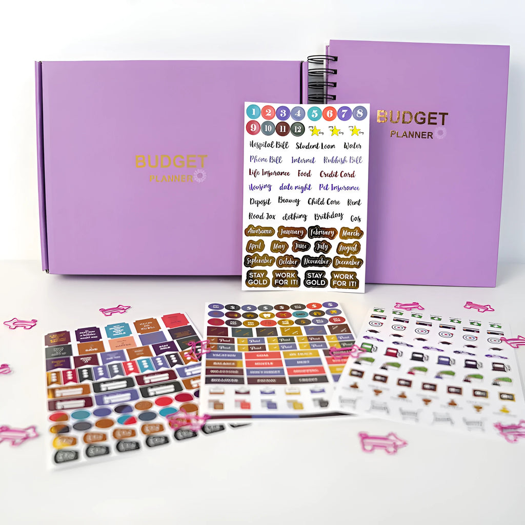 Purple coil-bound financial planning notebook with stickers, pen, and paper clips for monthly budget tracking