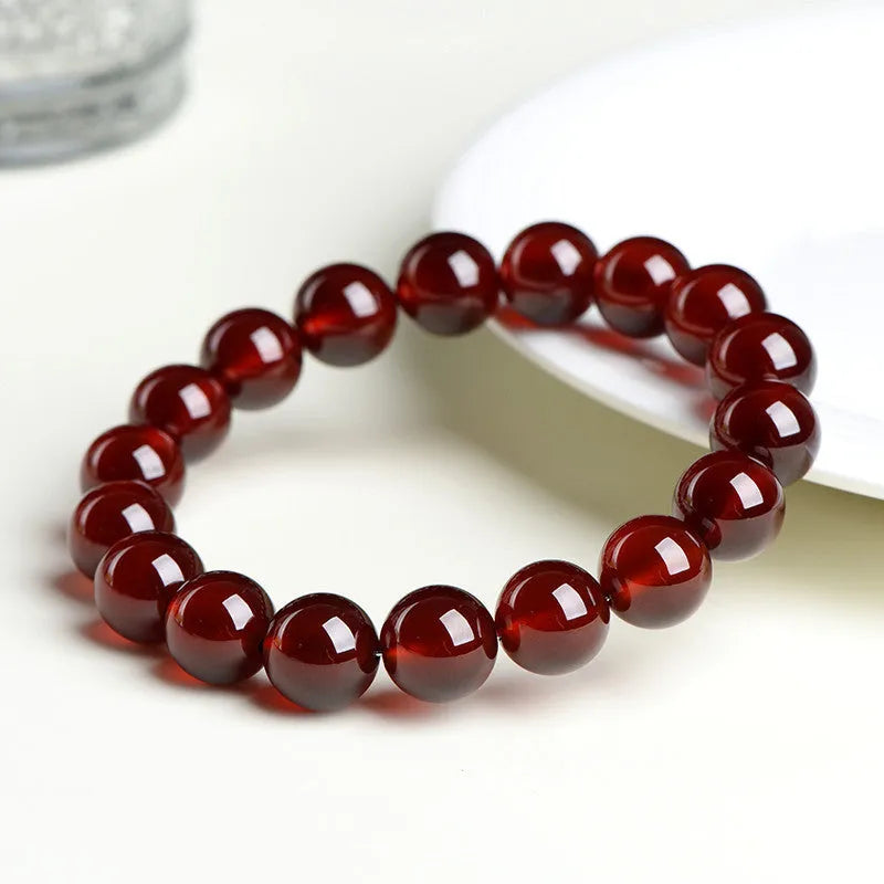 Natural orange red garnet ball bracelet with a silver Ruyi charm on a crystal beaded strand.