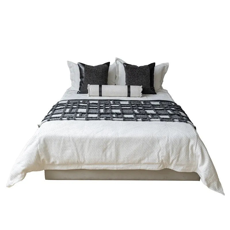 Modern minimalist grey and white plaid bed runner set with pillowcase and round leather pillow on bed