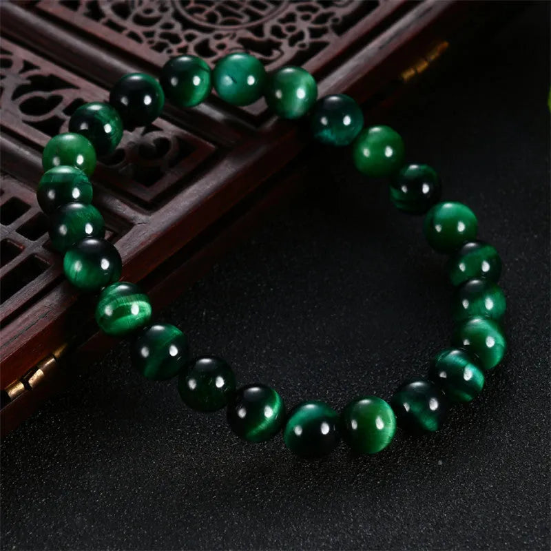 Green tiger eye stone bracelet with polished geometric beads on a wrist.