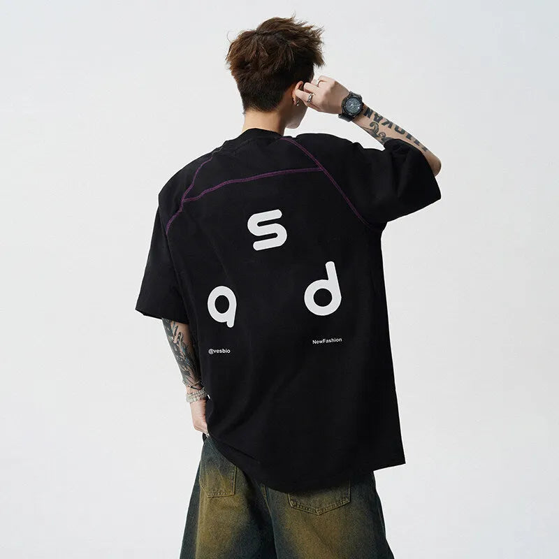 Men's loose-fit black cotton t-shirt with a white printed letter design on the front, showing short sleeves and a round neck.