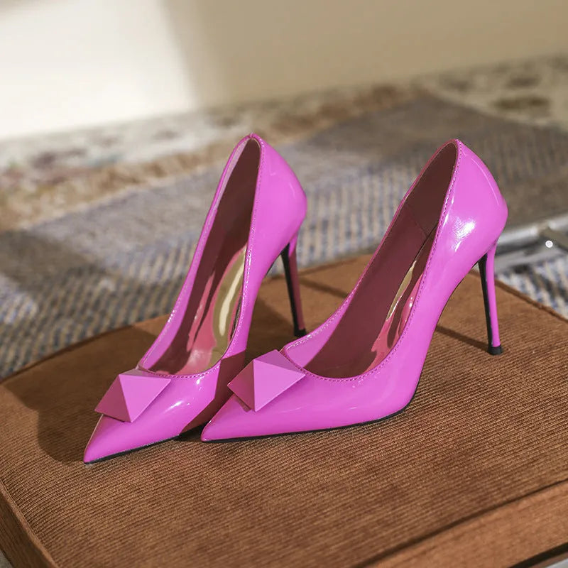 Pink patent leather women's stiletto high heels with pointed toe and buckle detail on a rubber sole.