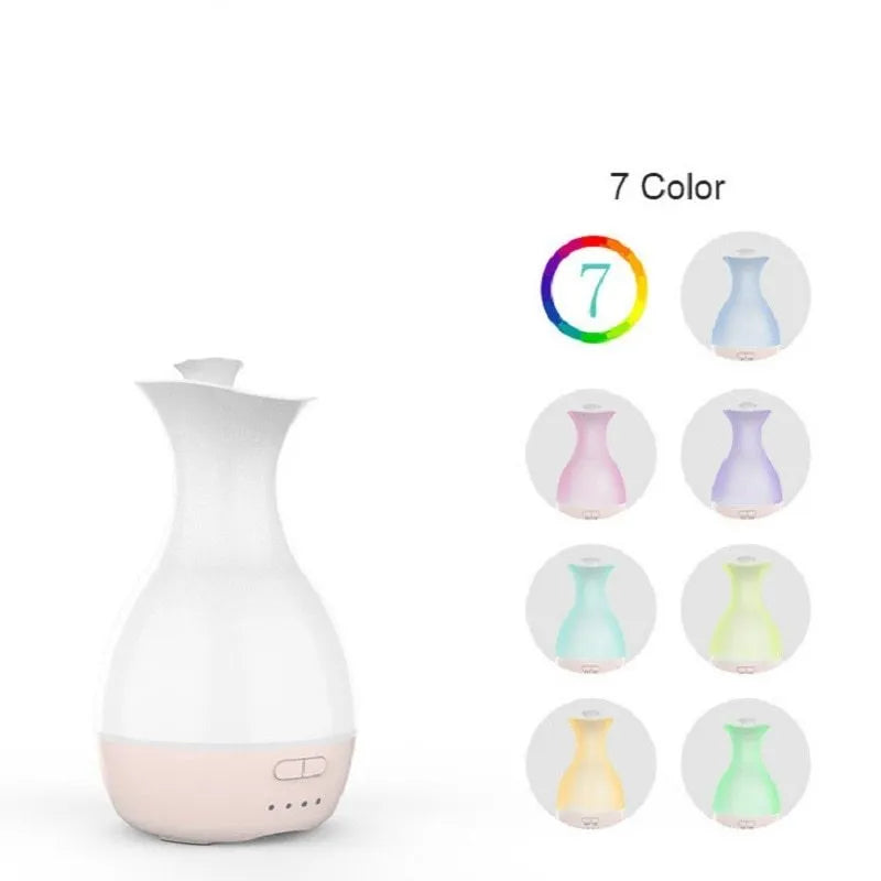 White or pink ultrasonic essential oil diffuser with water tank and multicolour LED night light on a table.