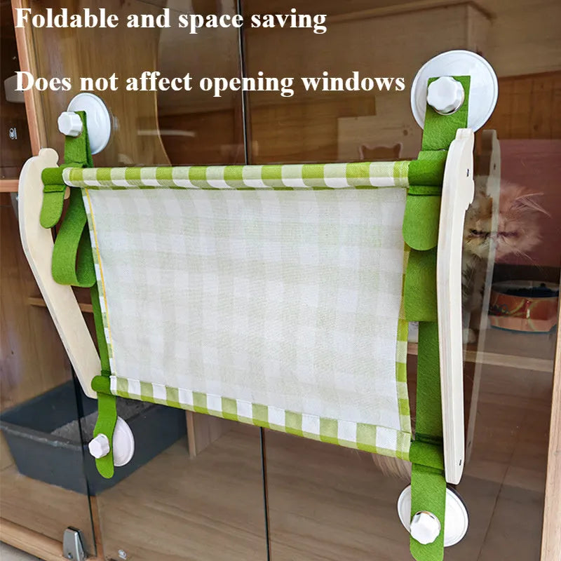 Pink wooden cat hammock with suction cups attached to a window, showing a removable cat paw print fabric seat.