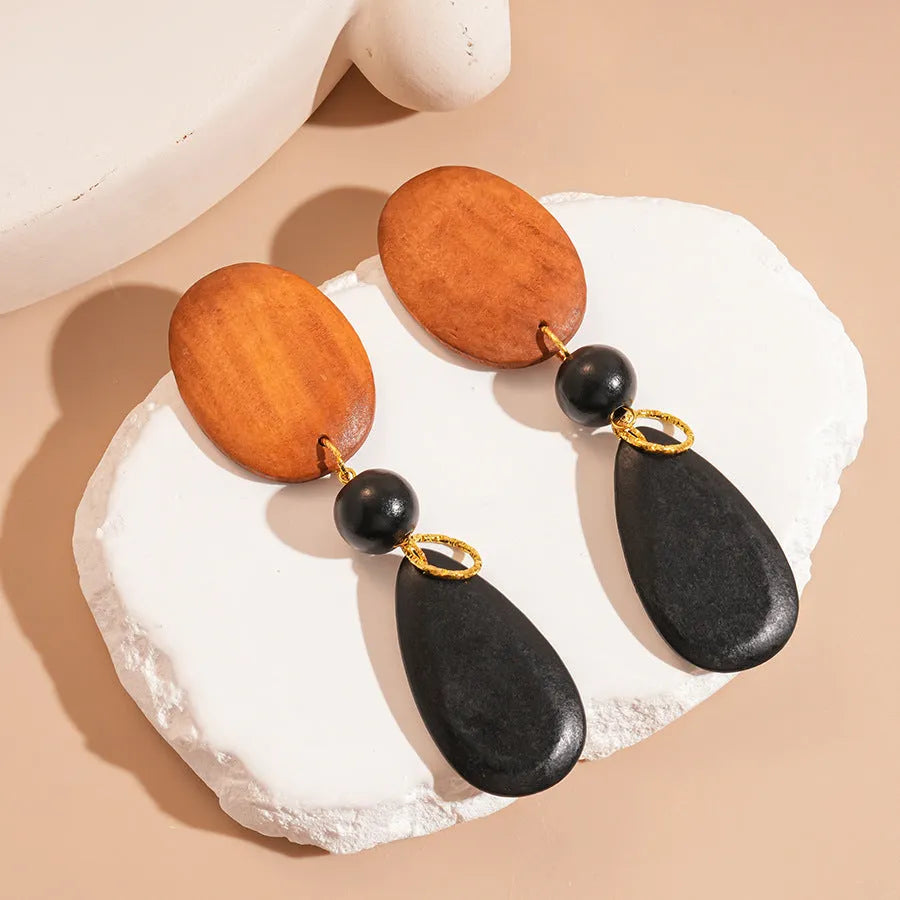 Pair of brown and black wooden elliptical retro style earrings on a silver backing.