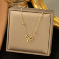 Gold-coloured titanium steel necklace with bow design and cross chain construction