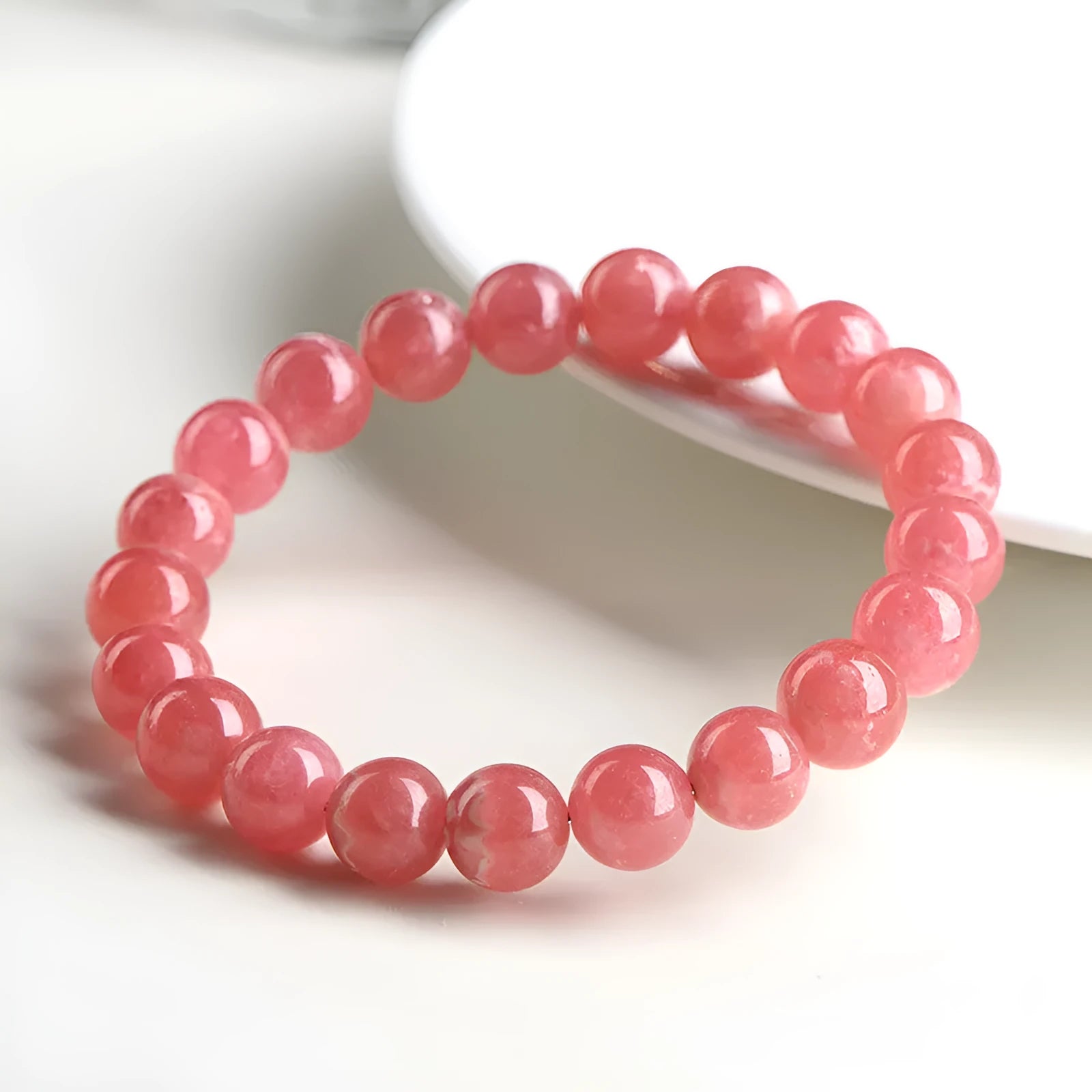 Women's red rhodochrosite crystal bracelet with geometric beads and a longevity lock clasp on a wrist.