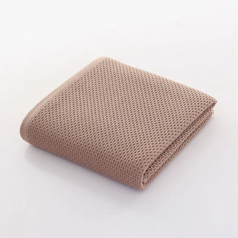 All-cotton jacquard bath towel in beige, 70x140cm, folded on a bathroom shelf