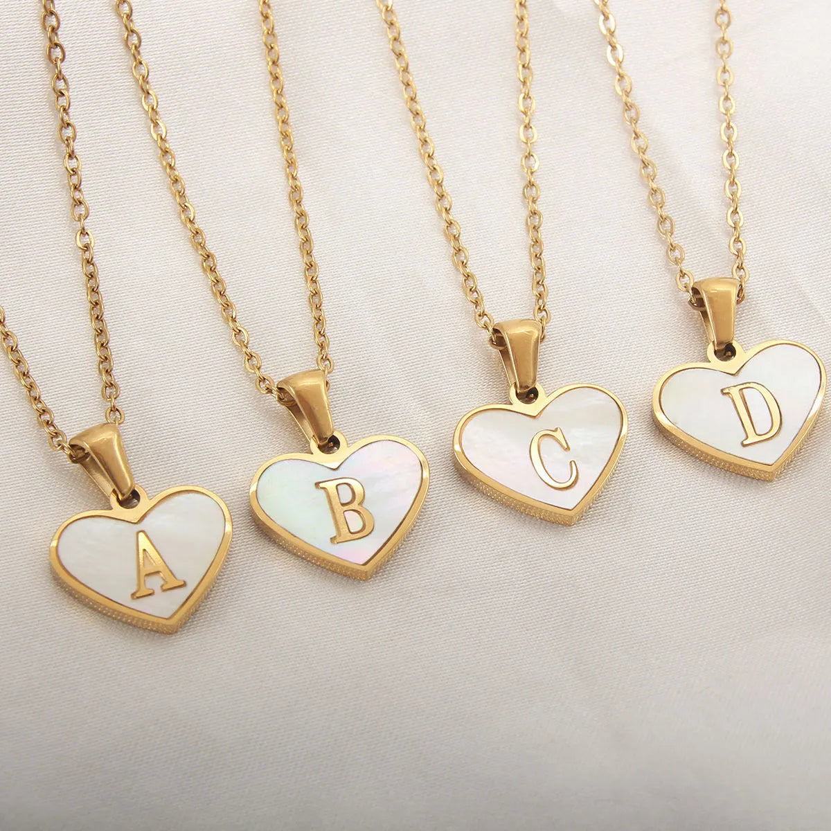 Gold plated heart-shaped necklace with a personalised initial letter and white shell detail on a 50cm adjustable chain.