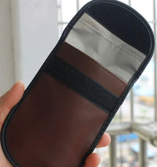 Black microfibre Faraday pouch for blocking car key, phone, and bank card signals, shown with a key fob inside.
