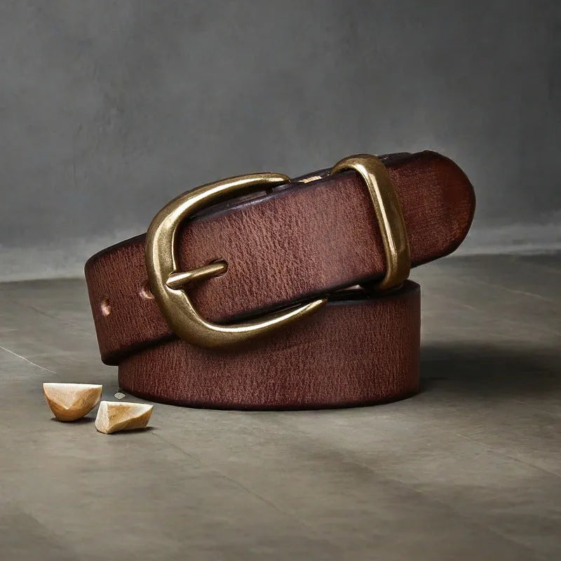 Men's black cattlehide leather belt with a copper pin buckle on a jeans background.