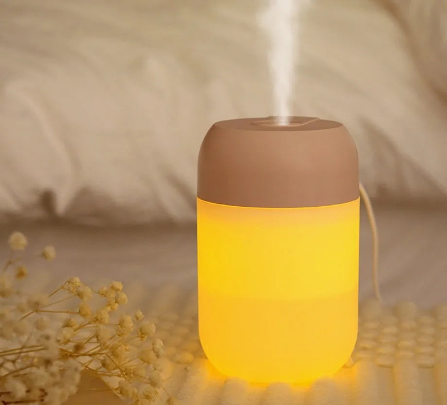 Small white cylindrical USB humidifier with aromatherapy function on a wooden desk.