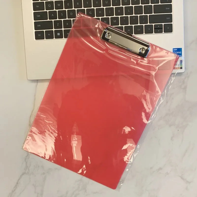 A4 transparent plate clipboard with metal clip, shown in blue colour on a desk with paper.