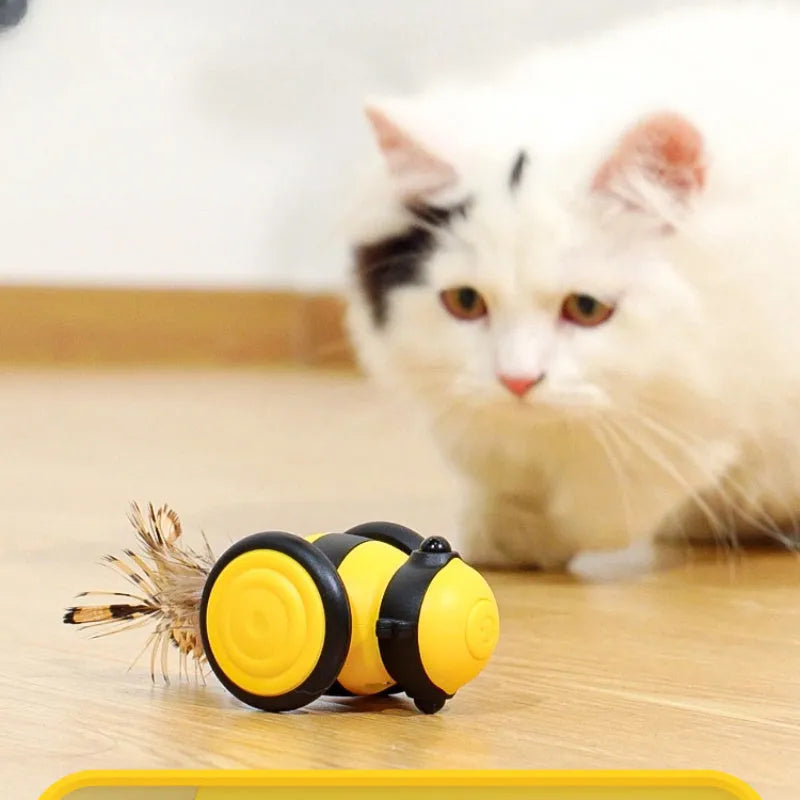Pink and yellow bee-themed electric cat toy with feather attachment on floor