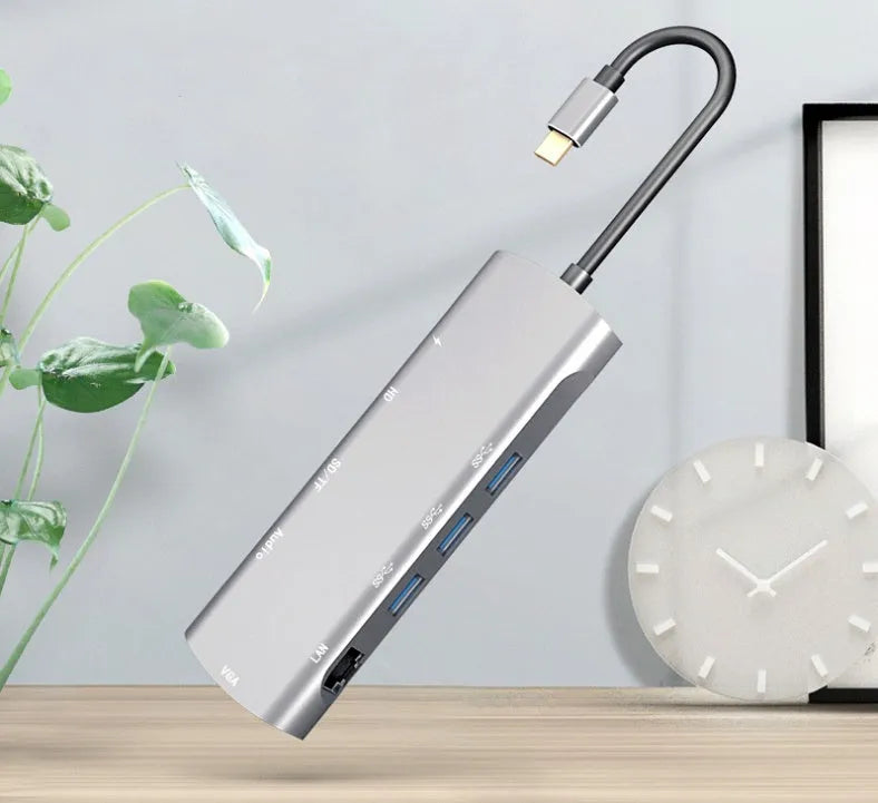Grey aluminium USB-C docking station showing HDMI, VGA, USB 3.0, PD charging, and card reader ports.